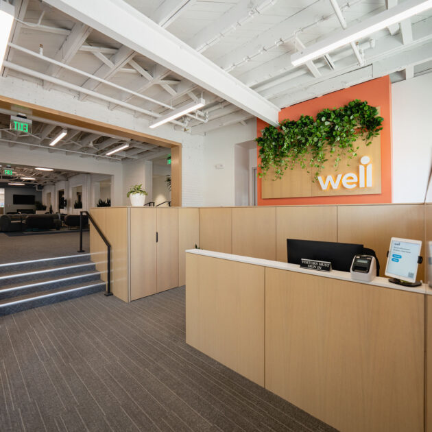 The lobby of the Well office in Downtown Chapel Hill. And open concept space with a light wooden sign that reads "well"